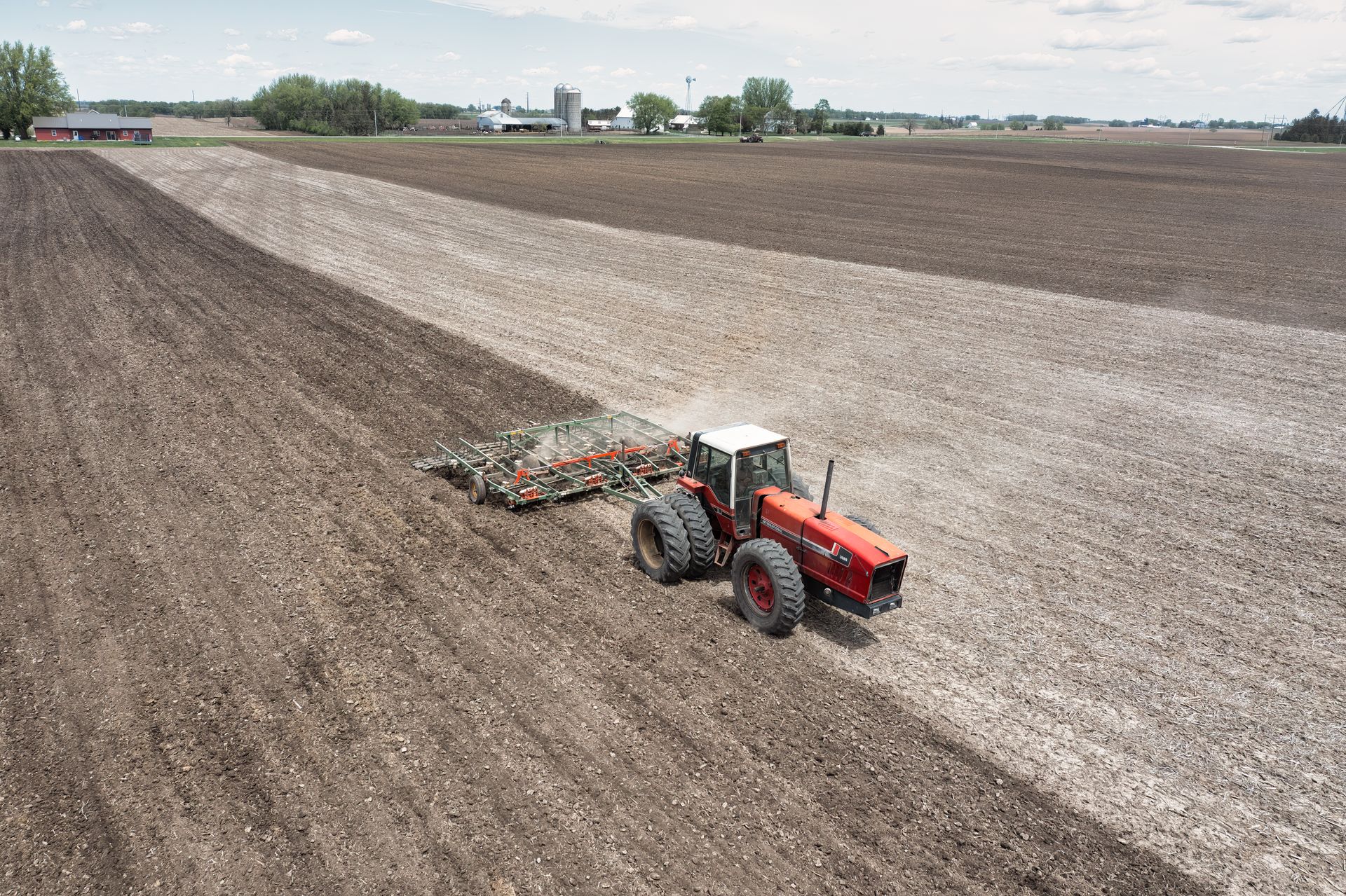 Red tractor preparing a broad field